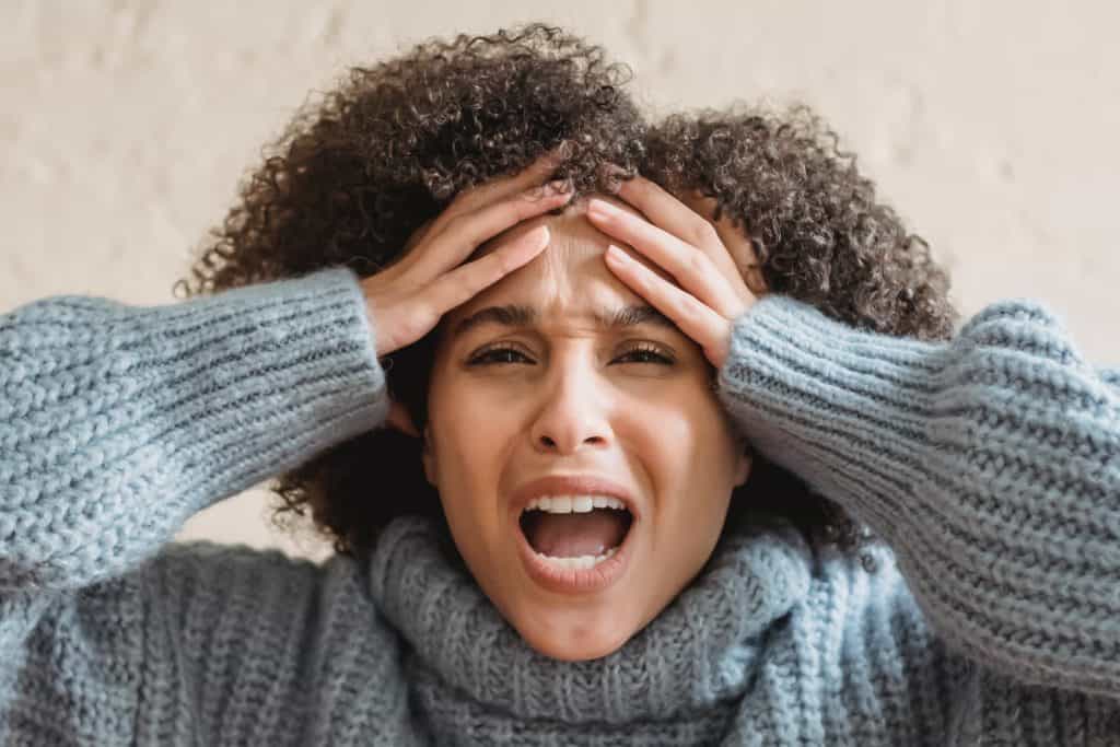 woman holds her hands to her head in anger