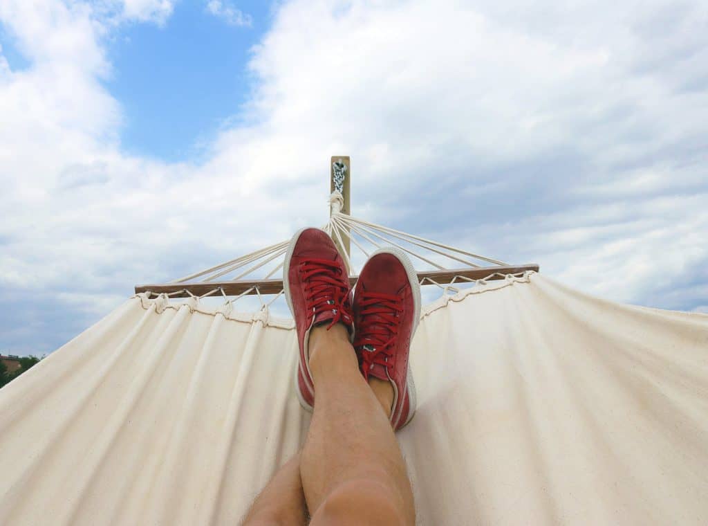 someones feet resting in a hammock under a blue sky