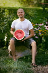 Matt Bennett sitting outdoor with a watermelon